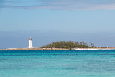 Lighthouse by sea against sky