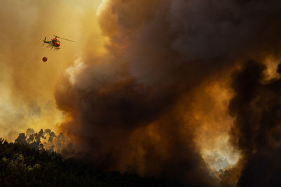 Firefighter helicopter fighting against a forest fire during day in braga, portugal.