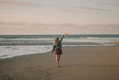 Full length of boy on beach against sky during sunset