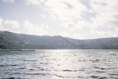 Scenic view of sea and mountains against sky