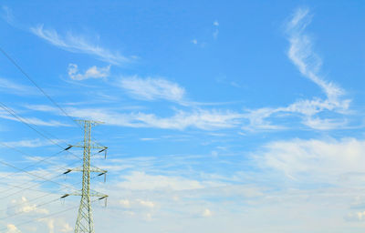 Low angle view of electricity pylon against blue sky