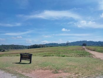 Empty bench on field against sky