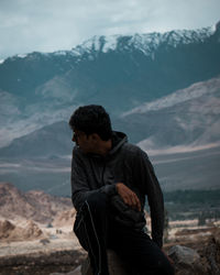 Man sitting on land against mountains