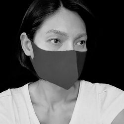 Woman wearing mask looking away against black background