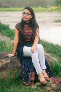 Portrait of young woman sitting on rock