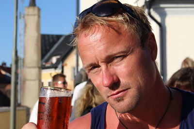 Close-up portrait of man having beer in city