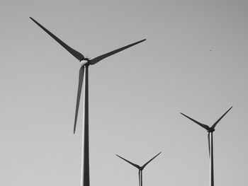 Low angle view of windmills against clear sky