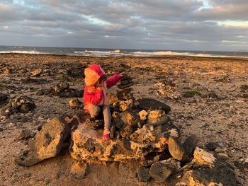 Girl standing on rock by sea against sky