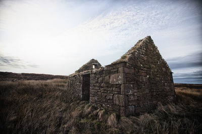 Old ruin building on field against sky