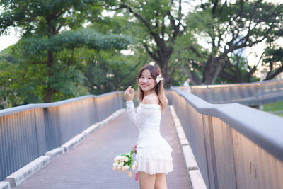 Young woman standing against railing