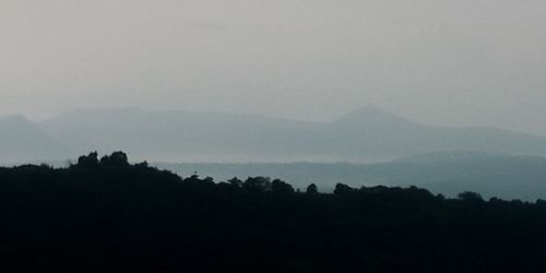 Silhouette trees on mountain against sky