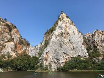 Low angle view of rocks by lake against clear sky