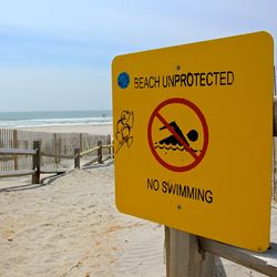 Information sign on beach against sky