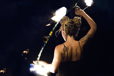 Woman holding burning ring while performing at night