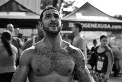 Worried shirtless man looking up at carnival