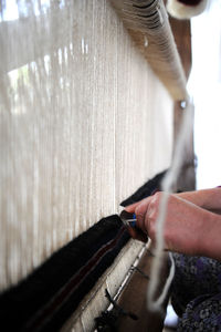 Cropped hands of woman weaving carpet