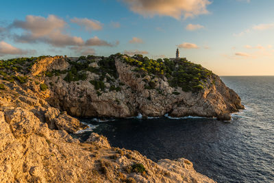 Rock formation on sea against sky during sunset