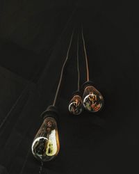 Low angle view of illuminated lighting equipment against black background