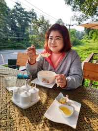 Portrait of smiling overweight woman having meal at table