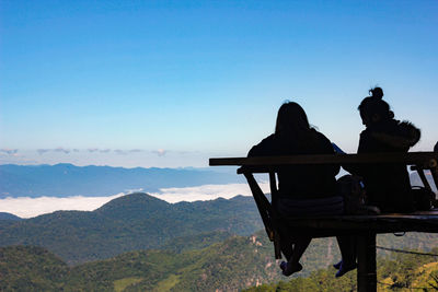 Silhouette friends couple sitting at observation point against .sky