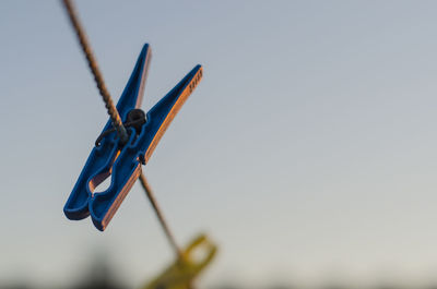 Close-up of clothespin on clothesline against sky