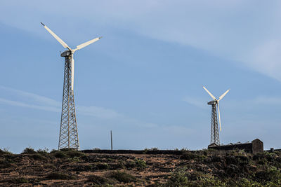 Low angle view of windmill on field against sky