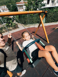 Portrait of boy sitting on swing at playground