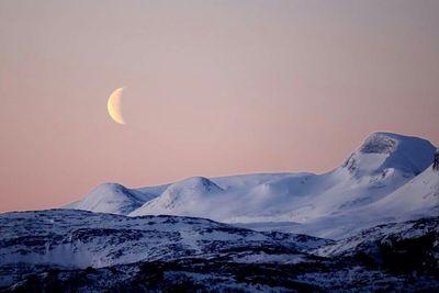 Scenic view of snow covered mountains against sky during sunset