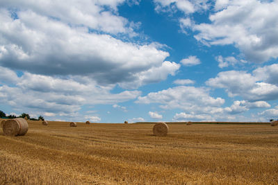 Hay bales on field against sky