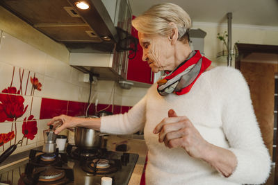 Senior woman preparing coffee in kitchen at home