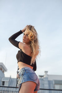 Beautiful young woman standing against clear sky