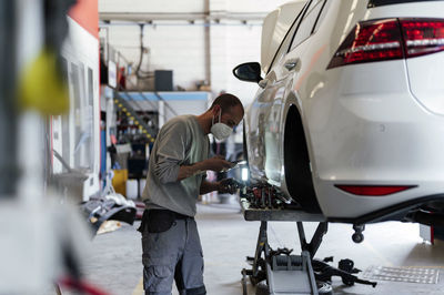 Mechanic photographing car part in garage