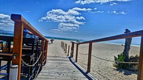 Chairs on beach against blue sky