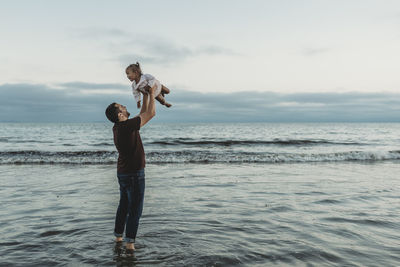 Dad throwing his daughter in air in the ocean