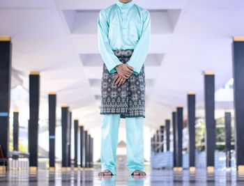Low section of man in traditional clothing standing under bridge
