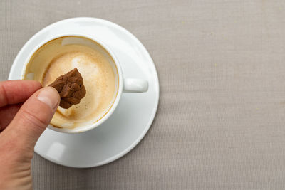 Cropped image of hand holding coffee cup on table