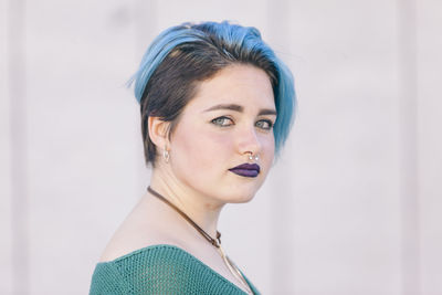 Portrait of young woman looking away against wall