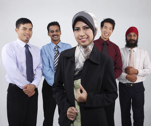 Portrait of smiling colleagues standing against white background