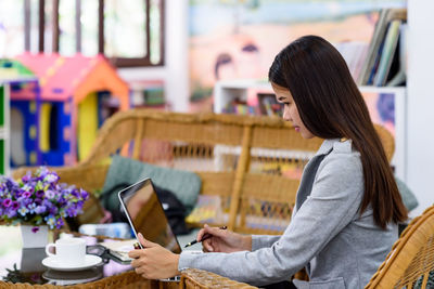 Side view of woman using phone on table
