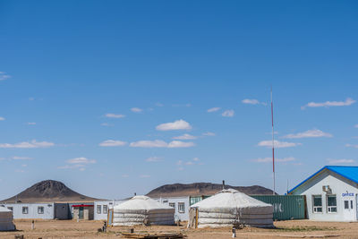 Houses by buildings against blue sky