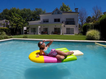 Happy girl on inflatable ice cream raft in swimming pool