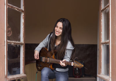 Smiling young woman playing guitar