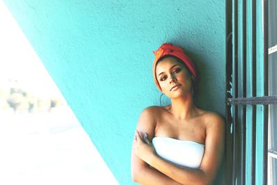 Portrait of young woman standing against wall