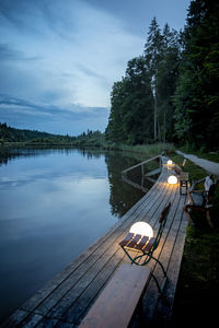 View of illuminated lamps by lake against sky with reflection 