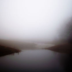 Scenic view of lake against sky during foggy weather