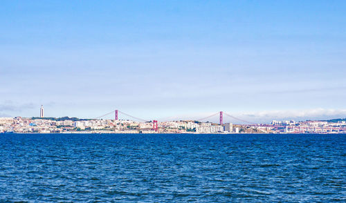 View of city at waterfront against cloudy sky