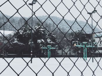 Close-up of chainlink fence against sky during winter