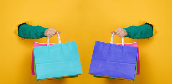 Directly above shot of multi colored shopping bags against yellow background