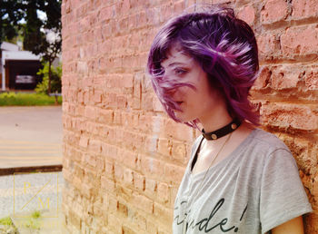 Woman in short pink hair standing by wall