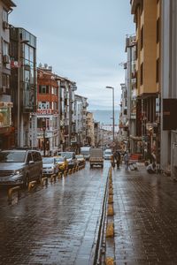 Wet street amidst buildings in city during rainy season